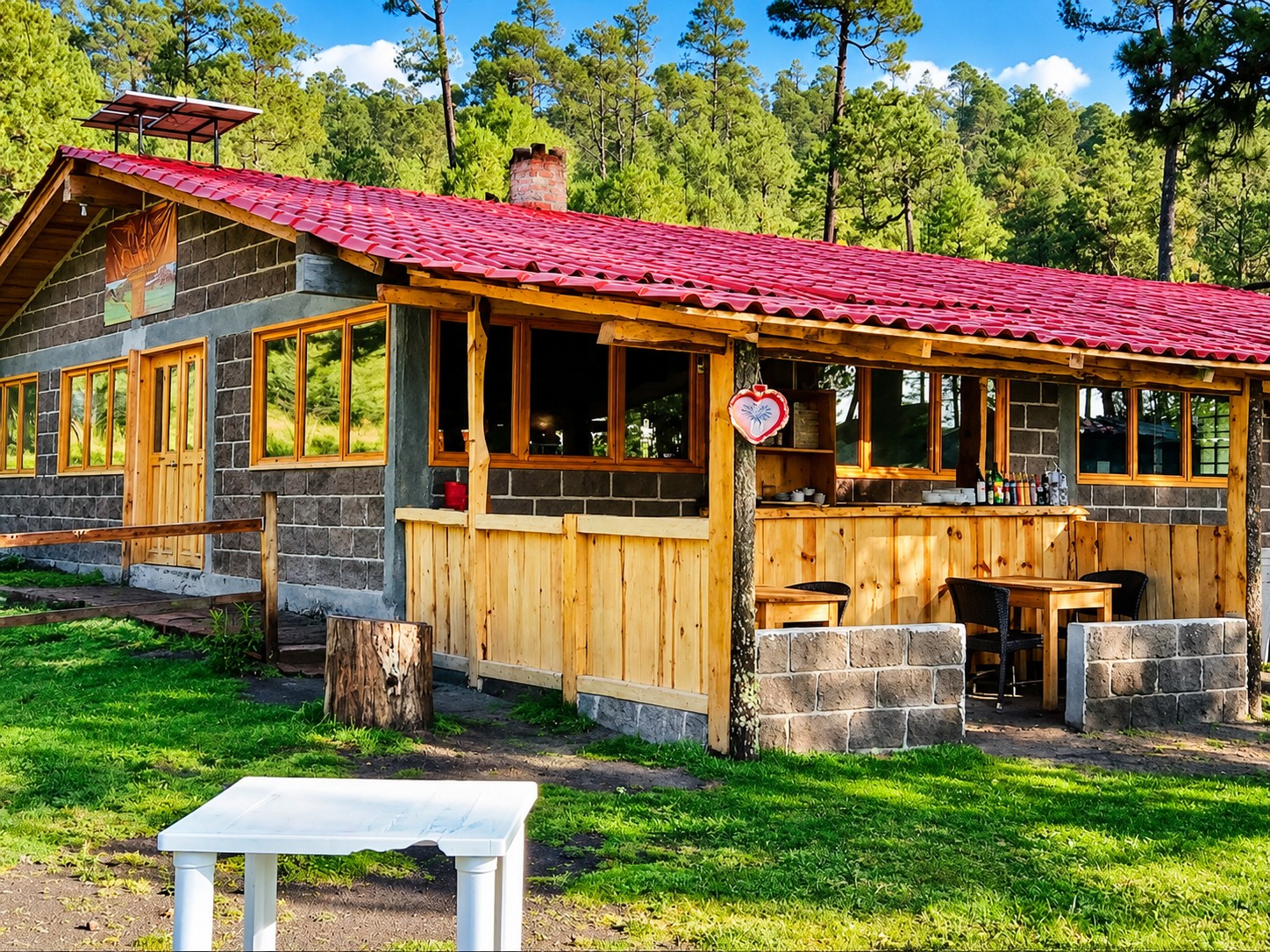 La Cabaña rodeada de árboles, con techo rojo y terraza de madera